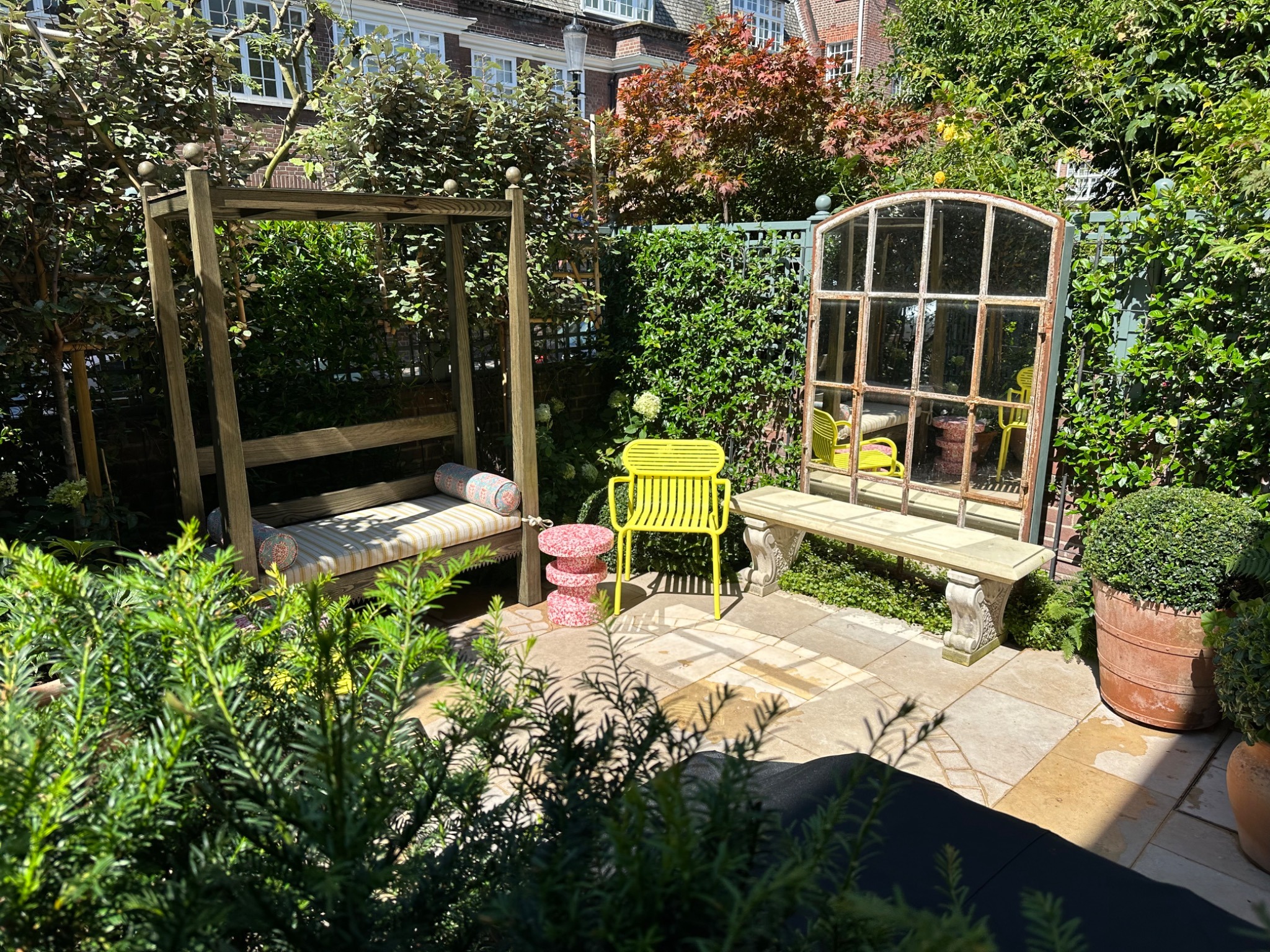 Sheltered garden seating area surrounded by trees, planting and trellis